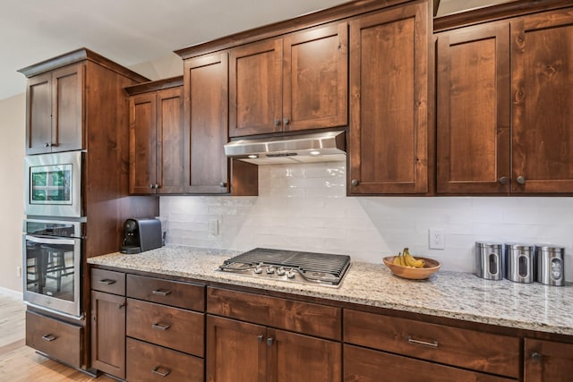 3623 Cove Point Cir NW, Prior Lake, MN 55372 - kitchen featuring appliances with stainless steel finishes, under cabinet range hood, light stone counters, and tasteful backsplash