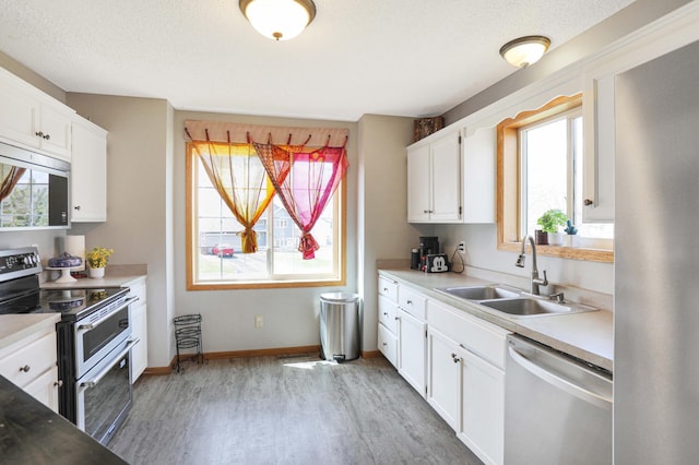 kitchen featuring light wood-type flooring, stainless steel appliances, plenty of natural light, and a sink