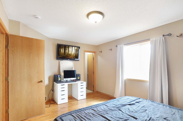 bedroom with a textured ceiling and light wood-style floors