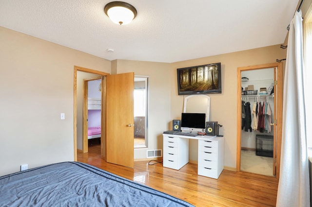 bedroom with a textured ceiling, visible vents, a closet, and light wood-style flooring