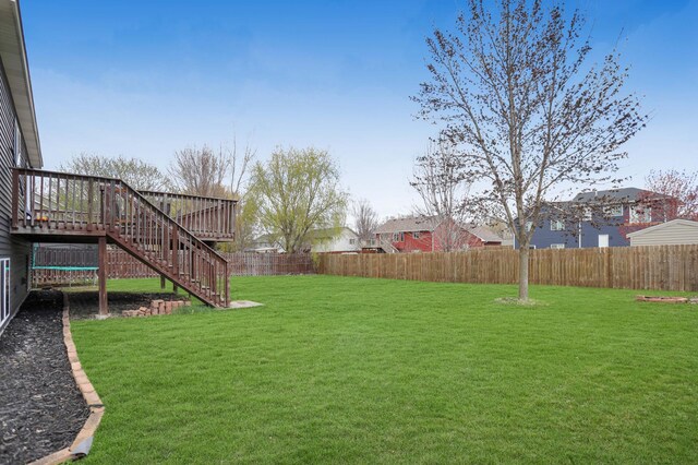 view of yard featuring a deck, stairs, and a fenced backyard