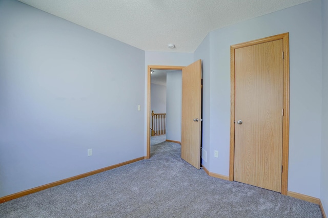 unfurnished bedroom featuring baseboards, a textured ceiling, and carpet