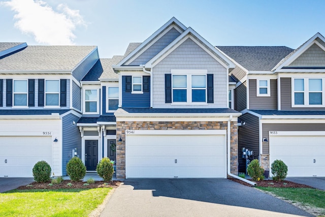 multi unit property featuring stone siding, driveway, and a garage