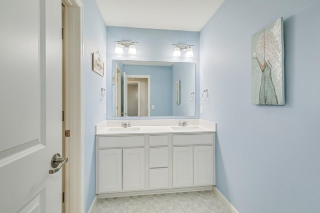 bathroom featuring baseboards, double vanity, and a sink