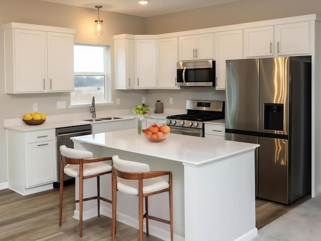 kitchen with a sink, white cabinets, stainless steel appliances, and wood finished floors