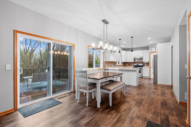 dining space with an inviting chandelier, recessed lighting, dark wood finished floors, and baseboards