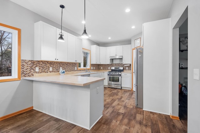 kitchen featuring decorative backsplash, a peninsula, a healthy amount of sunlight, and stainless steel appliances