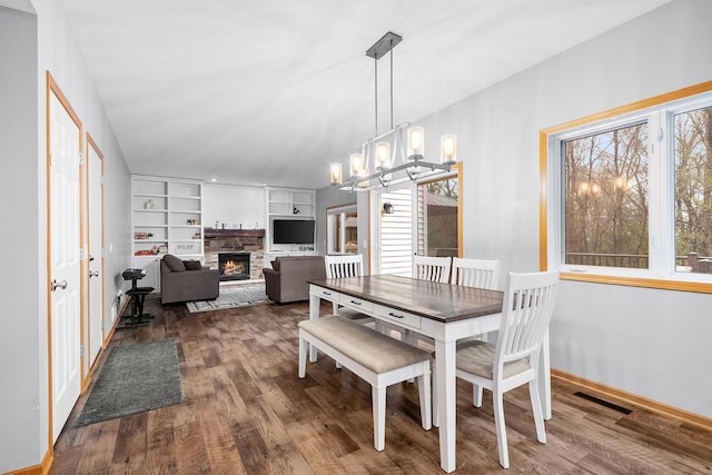 dining room featuring an inviting chandelier, wood finished floors, a healthy amount of sunlight, and a fireplace