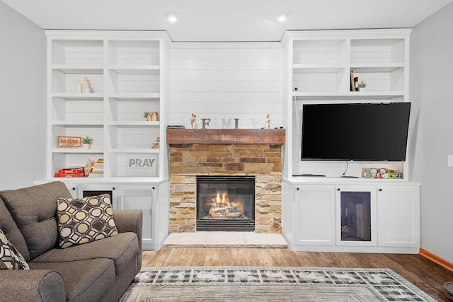 living room with a stone fireplace and wood finished floors