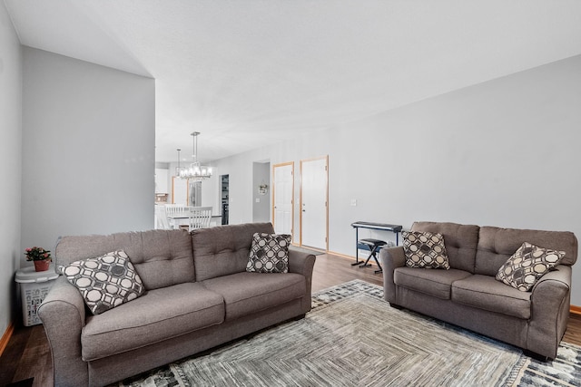 living area with baseboards, a chandelier, and wood finished floors