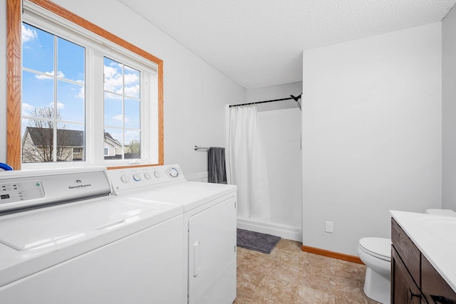 clothes washing area with a textured ceiling, laundry area, washing machine and dryer, and baseboards