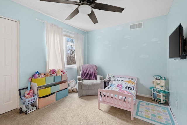 carpeted bedroom featuring a ceiling fan, a textured ceiling, and visible vents