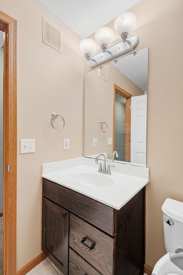 bathroom with toilet, a textured ceiling, visible vents, and vanity