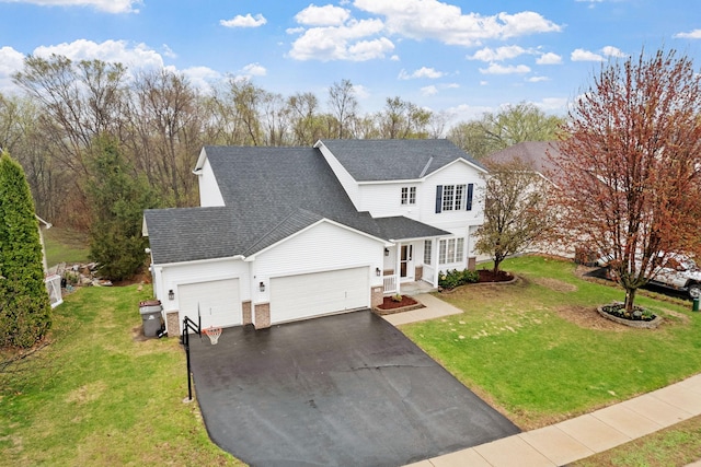 traditional home featuring an attached garage, driveway, a shingled roof, and a front lawn