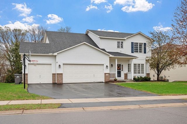 traditional-style house featuring brick siding, an attached garage, a front yard, and aphalt driveway