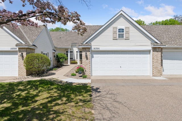 traditional-style home with brick siding, a shingled roof, and a garage