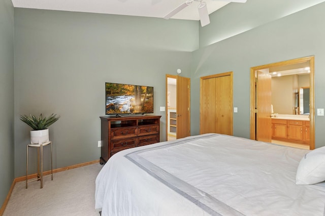 carpeted bedroom with ensuite bathroom, baseboards, a high ceiling, and a ceiling fan