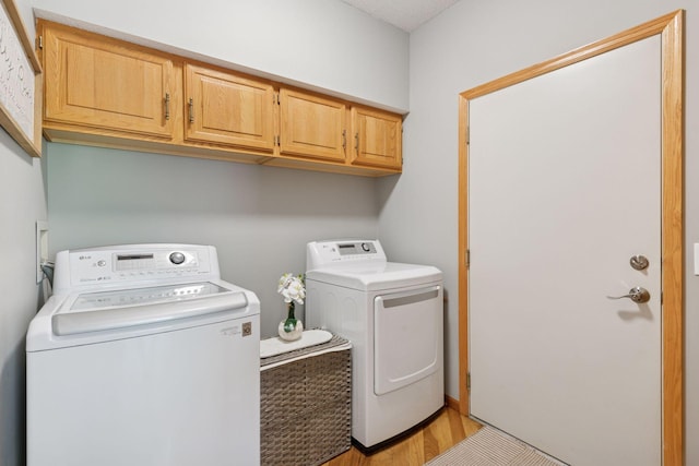 washroom with separate washer and dryer, cabinet space, and light wood-type flooring