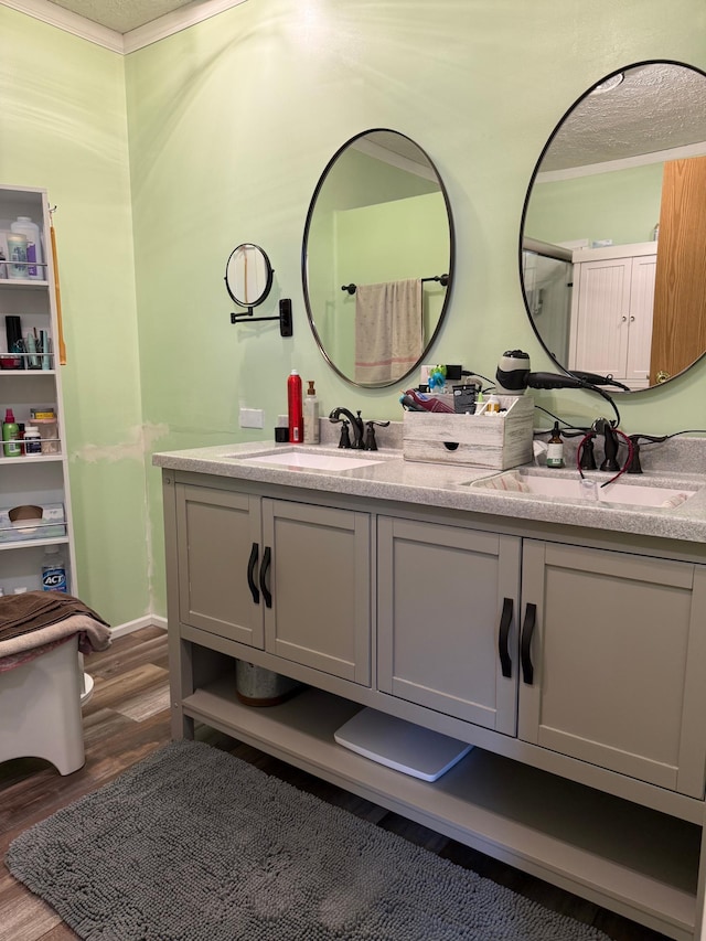 full bathroom with double vanity, a sink, and wood finished floors