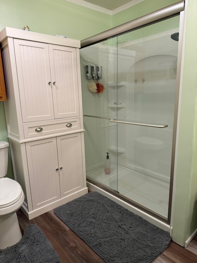 full bath with toilet, wood finished floors, and a stall shower