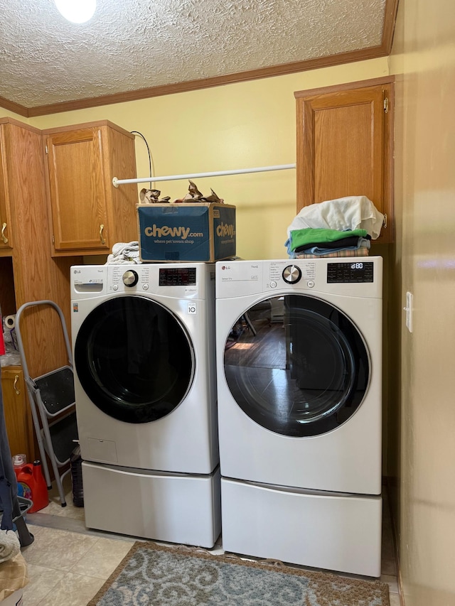 washroom with a textured ceiling, ornamental molding, separate washer and dryer, and cabinet space