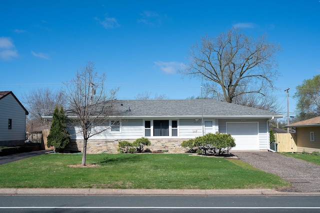ranch-style home with driveway, a front yard, fence, an attached garage, and a shingled roof