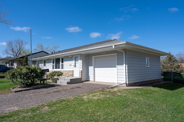 ranch-style house featuring an attached garage, gravel driveway, a front yard, and a shingled roof