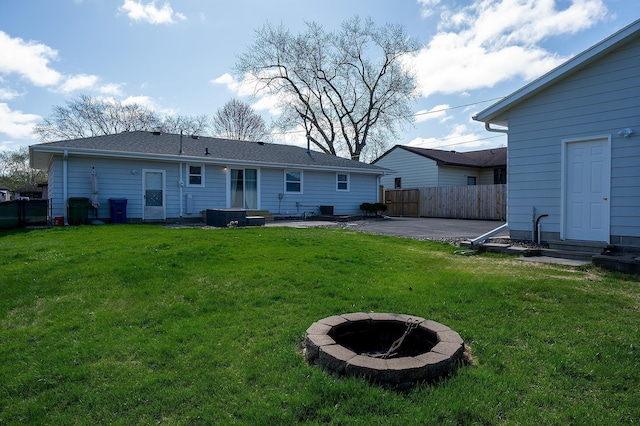 rear view of property featuring a lawn, fence, a patio, a fire pit, and entry steps
