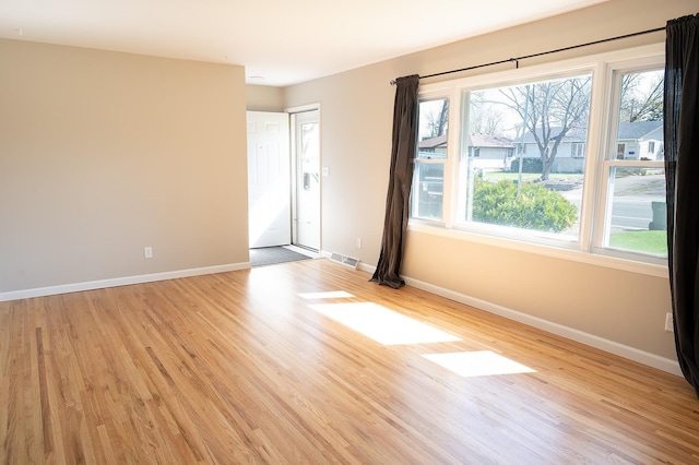 empty room with baseboards, light wood finished floors, and visible vents