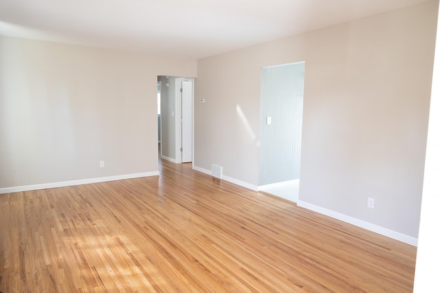 empty room featuring visible vents, light wood-style floors, and baseboards