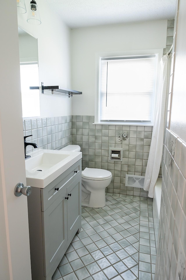 bathroom with tile patterned flooring, vanity, toilet, tile walls, and visible vents