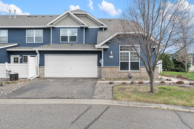 view of front of house with roof with shingles, stone siding, a garage, aphalt driveway, and central air condition unit