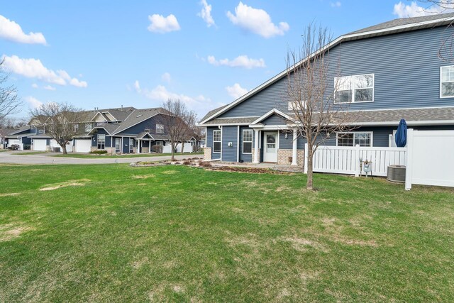 rear view of property with a lawn, cooling unit, and a residential view