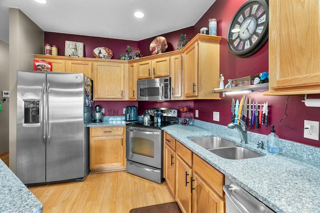 kitchen featuring a textured ceiling, appliances with stainless steel finishes, a sink, recessed lighting, and light wood-style flooring
