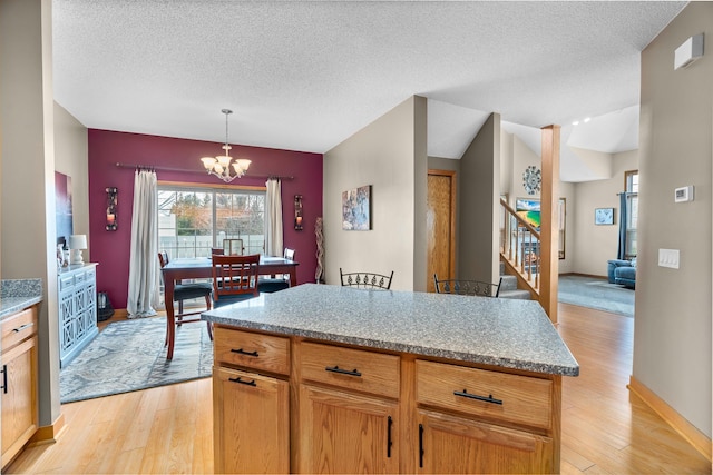 kitchen featuring a textured ceiling, light wood finished floors, a notable chandelier, and pendant lighting