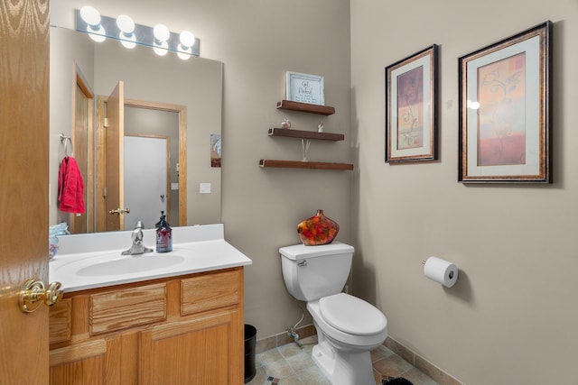 half bath featuring vanity, baseboards, tile patterned flooring, and toilet