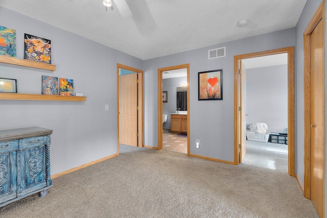 carpeted bedroom featuring baseboards, connected bathroom, a textured ceiling, and visible vents