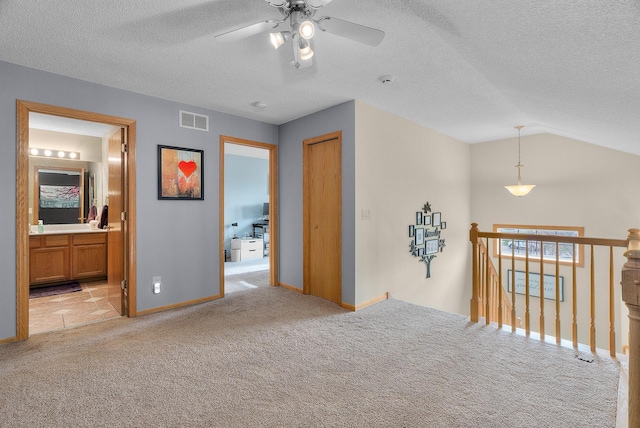 interior space featuring visible vents, baseboards, an upstairs landing, light carpet, and lofted ceiling