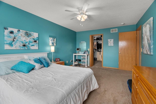 bedroom with visible vents, a closet, a textured ceiling, a spacious closet, and carpet