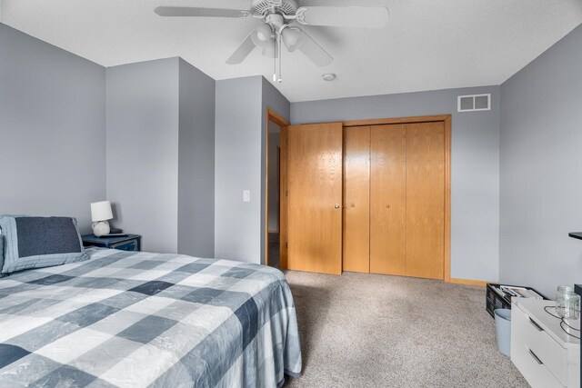 carpeted bedroom featuring a closet, ceiling fan, and visible vents