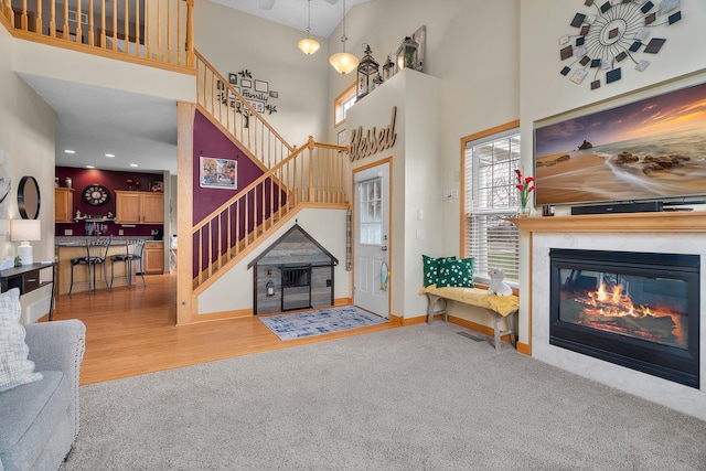 428 Hickory Ln N, Oakdale, MN 55128 - living area featuring stairs, a glass covered fireplace, a high ceiling, carpet, and wood finished floors