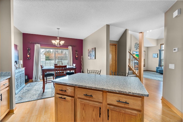 428 Hickory Ln N, Oakdale, MN 55128 - kitchen with a chandelier, light wood-style floors, a textured ceiling, hanging light fixtures, and a center island