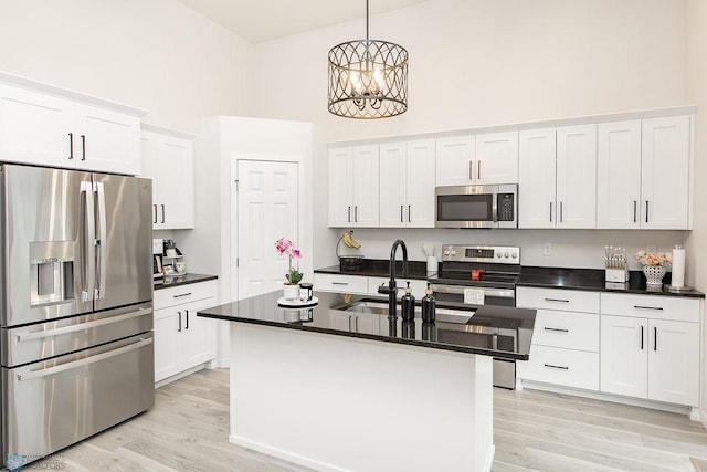 kitchen with stainless steel appliances, a high ceiling, white cabinetry, and a sink