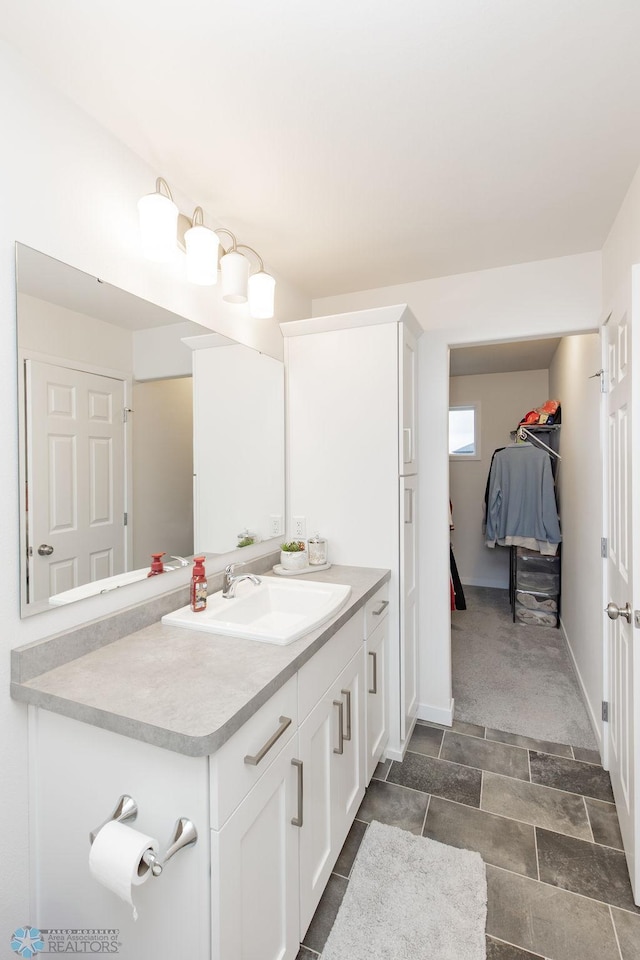 bathroom featuring vanity, baseboards, and a spacious closet