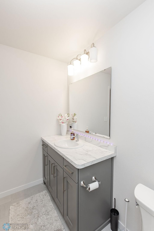 half bath featuring vanity, baseboards, and toilet