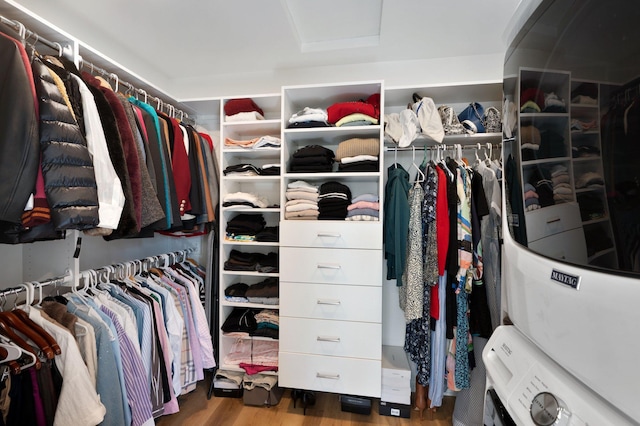 spacious closet with attic access, stacked washer and dryer, and wood finished floors