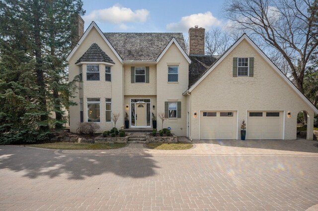 view of front of property with a garage, decorative driveway, and a chimney