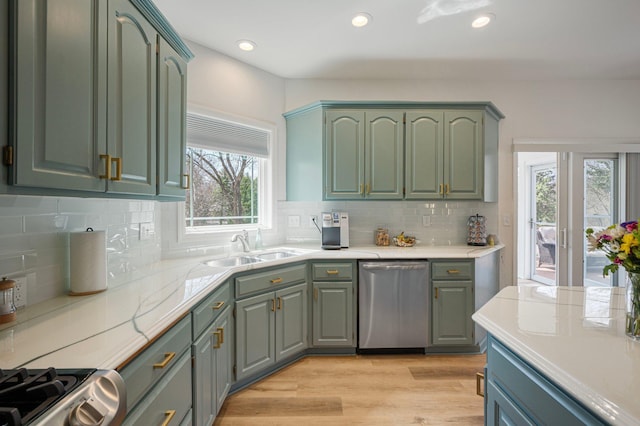 kitchen with a sink, light countertops, green cabinets, and stainless steel appliances
