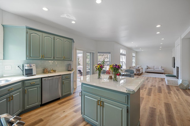 kitchen featuring stainless steel dishwasher, green cabinetry, decorative backsplash, and light countertops