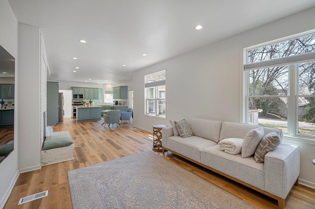 living room with recessed lighting, visible vents, a healthy amount of sunlight, and light wood-style floors